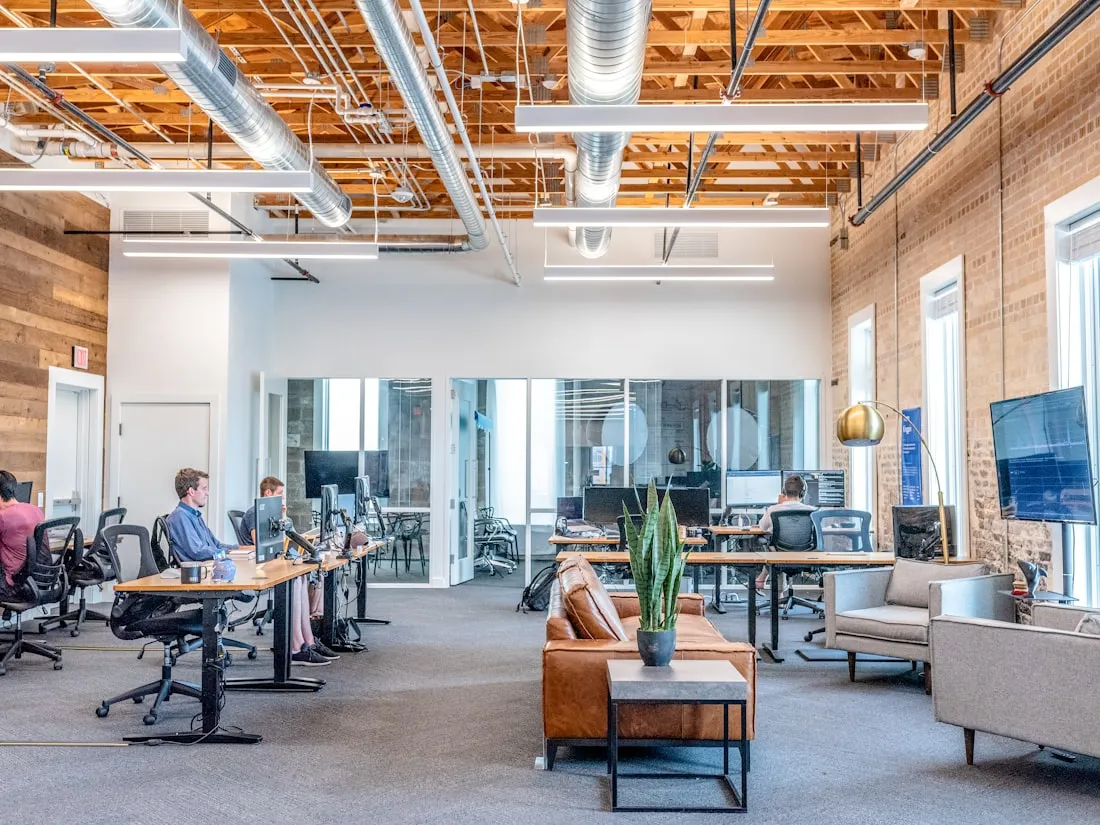 Bright open-plan coworking space with desks, plants and large windows